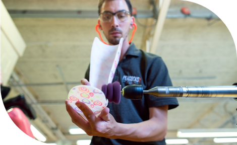 A man is using an industrial polisher to refine a product